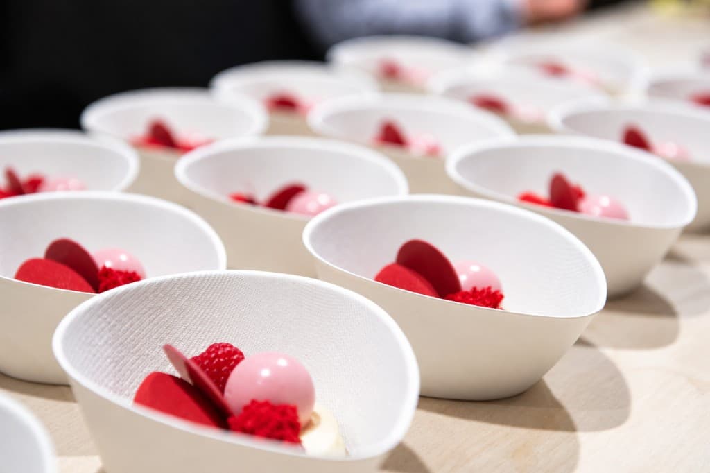 Small bowls of tartare being finished in a professional kitchen